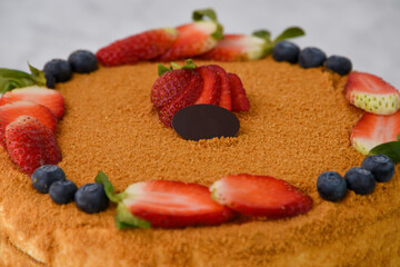 Classic Medovik Honey Layer Cake with Berries decorated with fresh strawberries and blueberries...