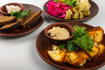 Traditional Eastern European cuisine served on rustic clay plates. A variety of homemade dishes including meat, potatoes, pancakes, dumplings and grilled vegetables, on a rustic background, top view.