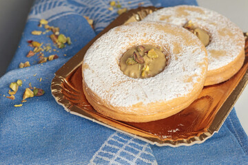 Shortbread dough biscuits with pistachio cream and nuts on gold paper plate. Dessert for party, celebration.