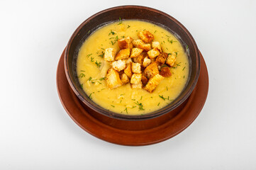 Creamy pea soup with golden croutons and fresh dill served in a clay bowl. Traditional homemade comfort food, top view, rustic style