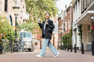 On the move in the moment as attractive woman walks through scenic streets balancing style ambition...