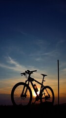Obraz premium mountain bike silhouette against sunset sky with blue gradient background