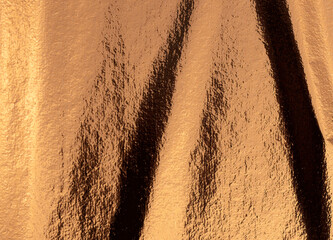 Golden and bronze foil texture with a glossy, shiny finish, creating a sleek, luxurious backdrop.