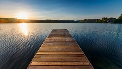 Fototapeta premium a close up of a wooden dock extending into the lake with ripples forming under soft sunlight in the background
