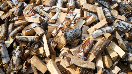 Stack of birch firewood with hand chopping block. Chopped firewood for winter. Lot of firewood - harvesting wood for heating the house. Horizontal photo. Chopped firewood background and texture 16x9.