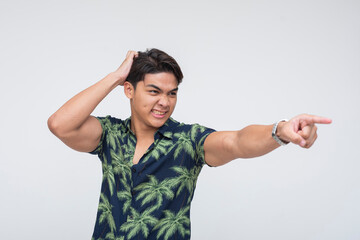 A furious and livid Southeast Asian man pointing aggressively while grabbing his head in...