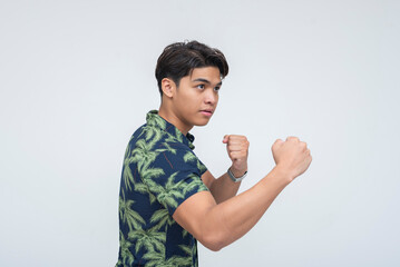 Side view of a serious Southeast Asian man in fighting stance with fists up, suggesting a heated...