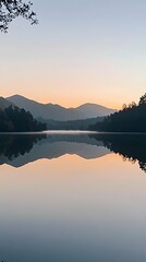 Obraz premium Serene lake with mountains in the background. The sky is a mix of orange and blue hues