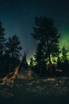 Traditionelles Lavvu im verschneiten Wald Schwedisch Lapplands w&auml;hrend einer klaren Winternacht mit Polarlichtern