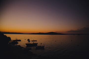 Silhouettes of boats by the shore before sunrise