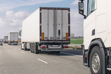 Cargo trucks driving on highway. Logistic transport on asphalt road. Freight vehicles in traffic....