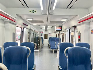Naklejka premium Interior view of a modern train with empty blue seats and bright lighting