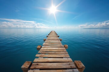 Obraz premium Weathered wooden pier stretching into calm ocean waters under bright sunlight at daytime.