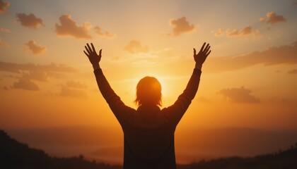 Fototapeta premium Person Celebrating Under an Orange Sunset With Arms Raised in a Serene Mountain Landscape