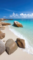 Large weathered rock on sandy beach beside calm water under clear daylight sky.