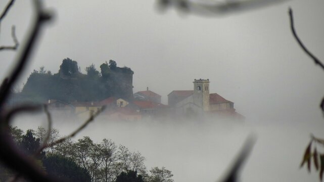 un borgo emerge nella nebbia lungo la via Francigena tra Vecchietto e Ponzano Superiore in Toscana