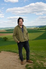 Attraktiver Mann  auf einem Hügel vor einer schönen Landschaft.