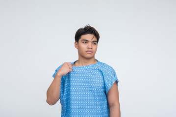 Southeast Asian male in blue gown tugging his neckline while looking away, showing signs of unease...