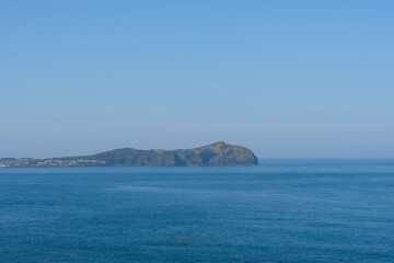 Seongsan Ilchulbong volcanic tuff cone panoramic view, calm mood, representing Jeju, South Korea, with blue sky and ocean