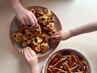 Children eagerly grab delicious pastries and a pie from a colorful plate during a joyful gathering. The warm atmosphere highlights togetherness and shared treats.