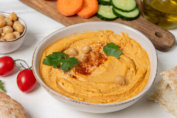 reamy hummus in a white bowl, garnished with chickpeas and herbs, paired with crispy flatbreads and olive oil, showcasing a vibrant and appetizing snack presentation