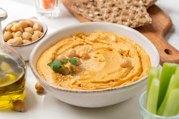 reamy hummus in a white bowl, garnished with chickpeas and herbs, paired with crispy flatbreads and olive oil, showcasing a vibrant and appetizing snack presentation