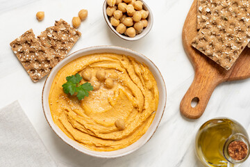 reamy hummus in a white bowl, garnished with chickpeas and herbs, paired with crispy flatbreads and olive oil, showcasing a vibrant and appetizing snack presentation