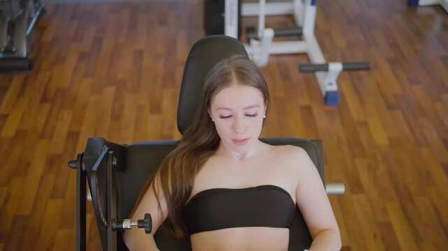 Young beautiful woman doing gluteal exercise on exercise machine. Sportswoman doing hip thrust on exercise machine.