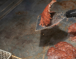 Chef flipping grilled smash burger patty on hot griddle