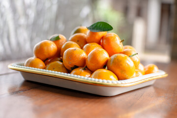Stack of Mandarin oranges in a square tray on a wooden table