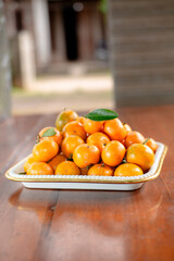Stack of Mandarin oranges in a square tray on a wooden table