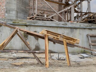 Wooden ramp holds materials at a construction site with exposed brick and scattered debris during...