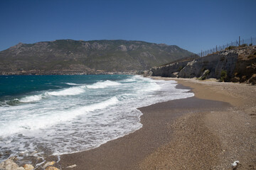 The beach of Loutraki stretches along the coast with sunbeds and clear blue waters, capturing the warmth and beauty of a Greek seaside summer.