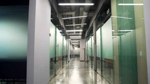 A modern sleek office corridor of a business center with doors and polished floors, gleaming, captured in motion. Video movement along an empty long hospital corridor with bright fluorescent lighting