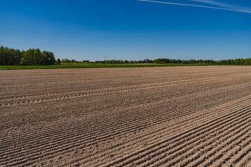 A rural landscape with a plowed empty field at the beginning of spring