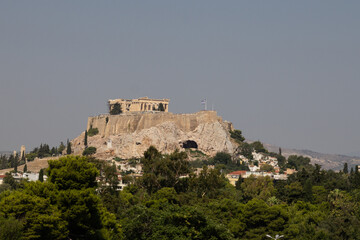 A scenic view of the Parthenon complex sitting atop the Acropolis hill in Athens, Greece. The ancient ruins stand prominently over the city.