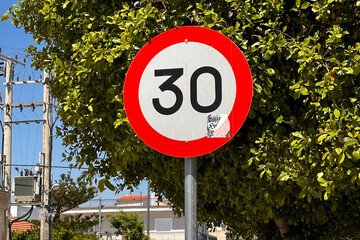 Speed limit 30 km/h road sign with red border on sunny day outdoors. 