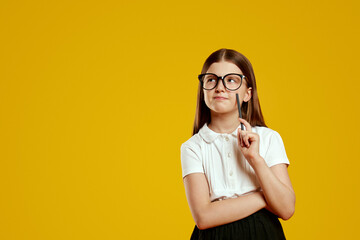 Curious child with glasses holding a pencil, contemplating a creative idea while looking at free...