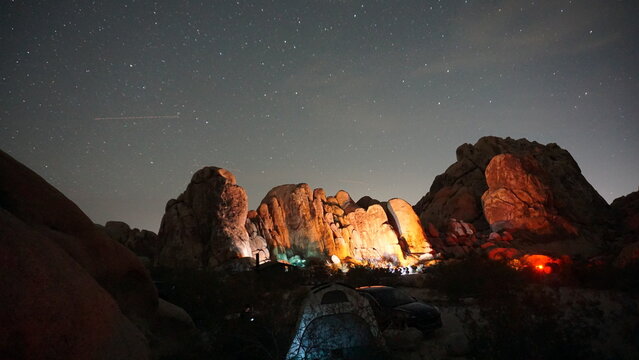 Campsite lights shining on large boulders under clear night sky
