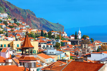 Vibrant view of Funchal, Madeira, showcases colorful buildings with tiled roofs cascading down...