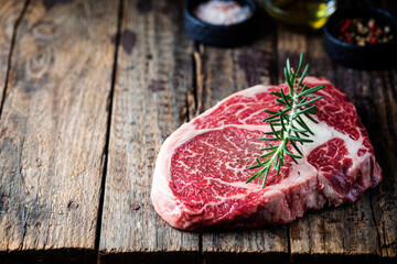 Raw fresh meat Ribeye Steak and seasonings on wooden background, rustic style