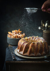 Rustic Style Apple Bundt Cake Sprinkled with Icing Sugar on old wooden table with woman hands