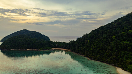 Aerial view of a stunning sunset above the Surin Islands. With golden hues reflecting on the calm...
