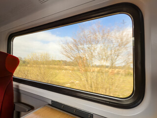 Large picture train window as it speeds past rural farmland
