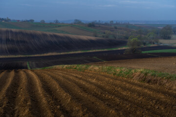 A picture painted by nature: furrows of the earth, black soil, blooming trees, a peaceful village, a cheerful village. Mother Earth our nourisher - concept