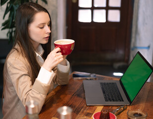 Woman using laptop and drinking coffee at cafe table
