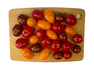 Cherry tomatoes in red, yellow, and burgundy colors arranged on a wooden cutting board, vibrant and fresh assortment of tomatoes on a kitchen surface, healthy food, vegetable photography.