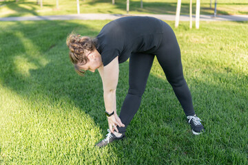 Mature woman warming up outdoors on grass
