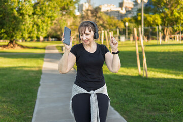 Obraz premium Musical escape: Mature woman dancing outdoors, lost in her music