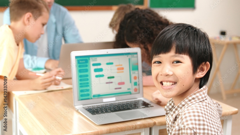 Poster energetic asian boy coding program and looking at camera in stem class while caucasian teacher and d